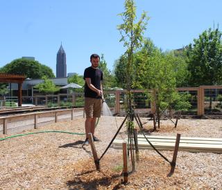 Elias Winterscheidt waters trees in the Community Garden